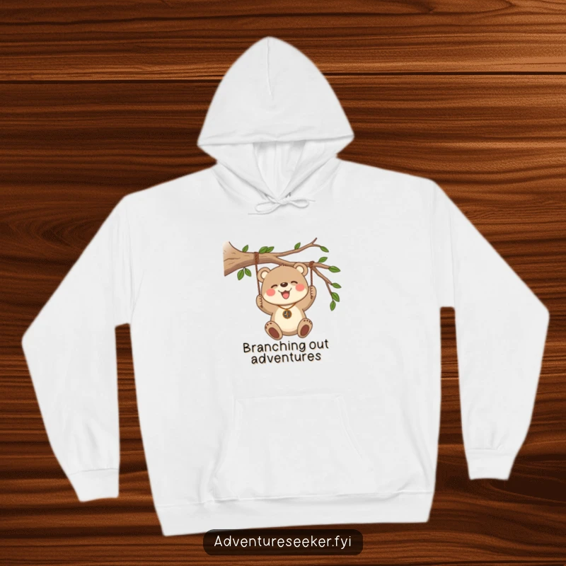 Funny Bear Cub Compass Hoodie. A joyful bear cub with a compass swings from a branch, offering warmth and adventurous spirit.