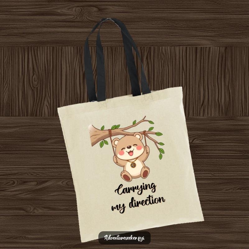 Funny Bear Cub Compass Tote Bag. A bear cub wearing a compass necklace swings from a branch, ideal for carrying adventure gear.